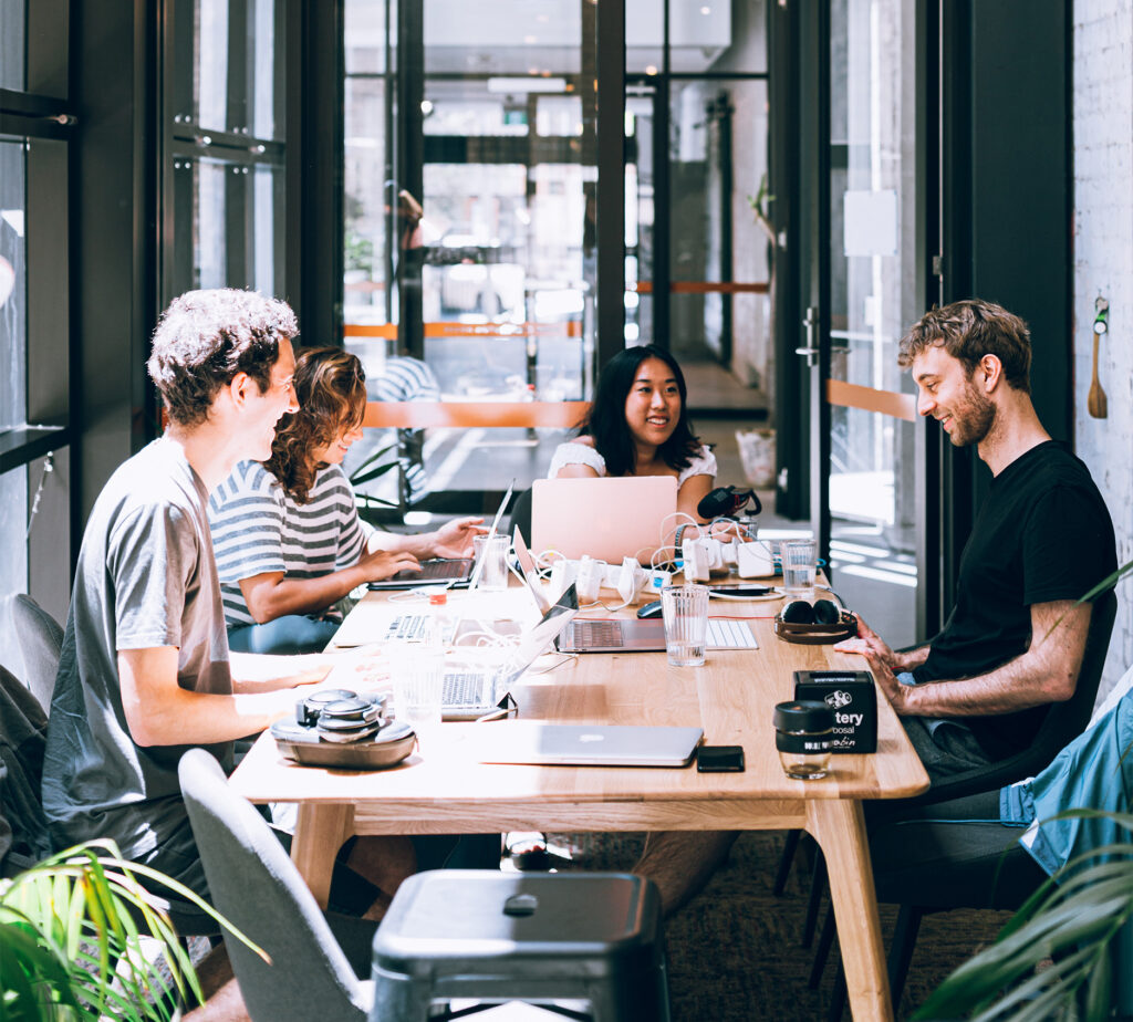 Cowoking yta med fyra unga männksor osm sitter vid vars en dator